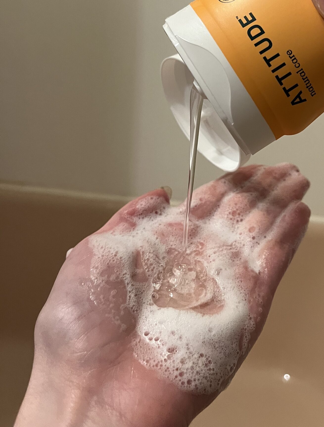 Dispensing liquid soap into a hand over a sink.
