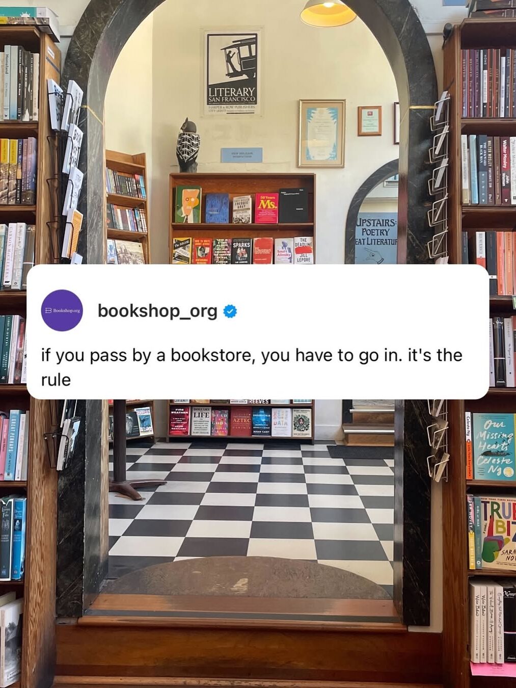 A bookstore entrance with a checkered floor, surrounded by shelves of books. A plaque by the door reads "Upstairs Poetry & Literature.