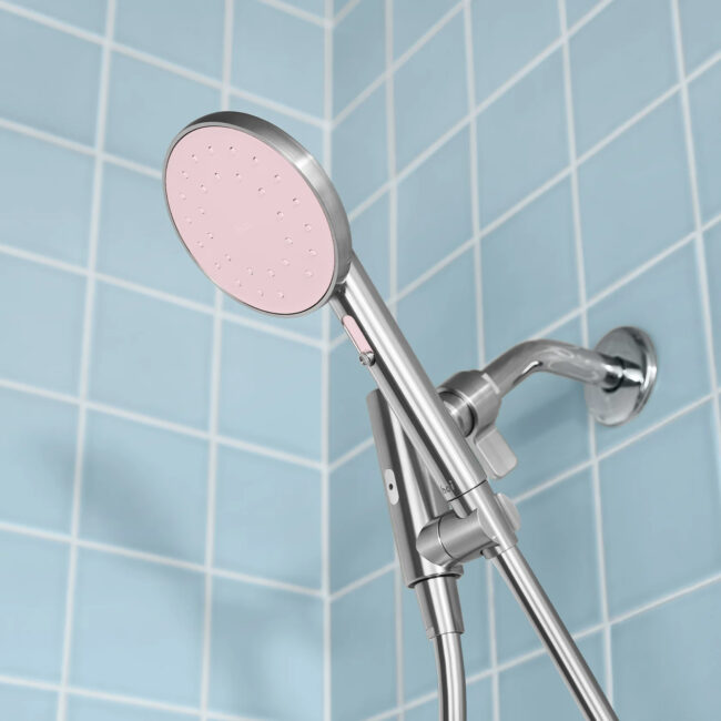 A Hai filtered showerhead in a blue tiled shower stall. 