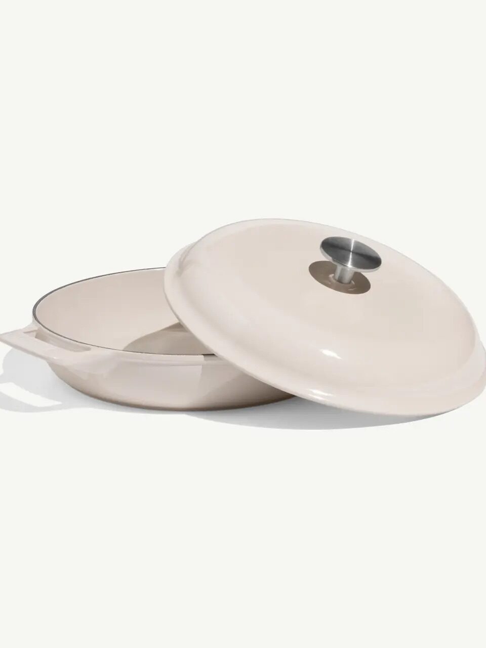 A beige enameled cast iron pan with a matching lid, featuring a metal knob, is shown on a plain white background.