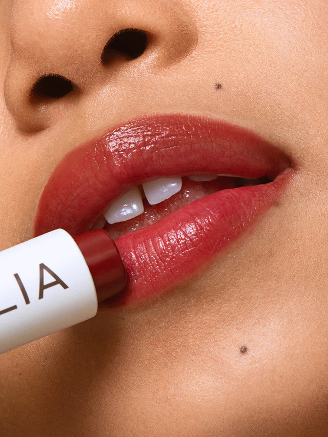 A model applying ILIA's Balmy Lip Tint on their lips. 