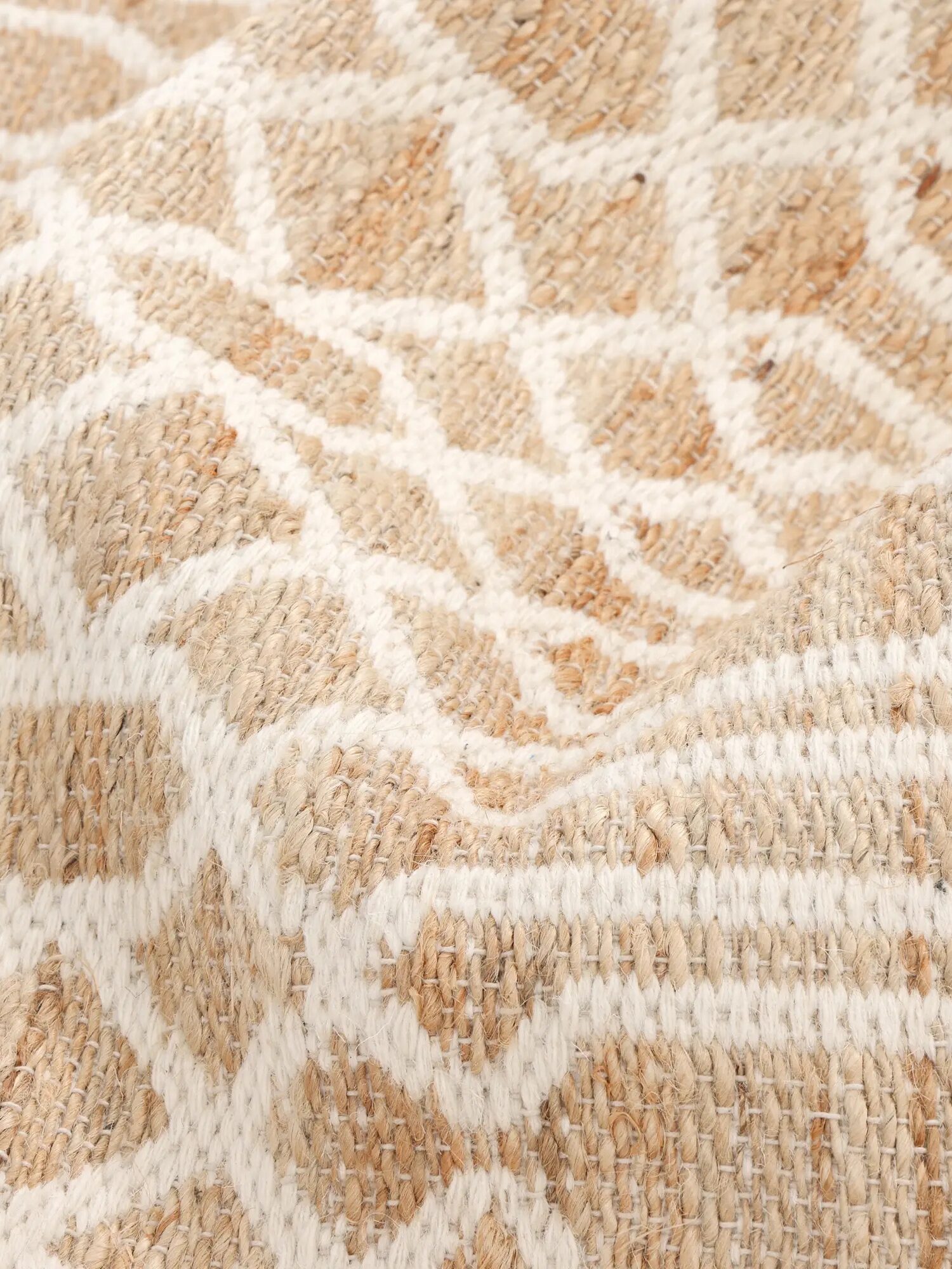 Close-up of a woven fabric with a beige and white geometric pattern, showing texture and raised areas on the surface.