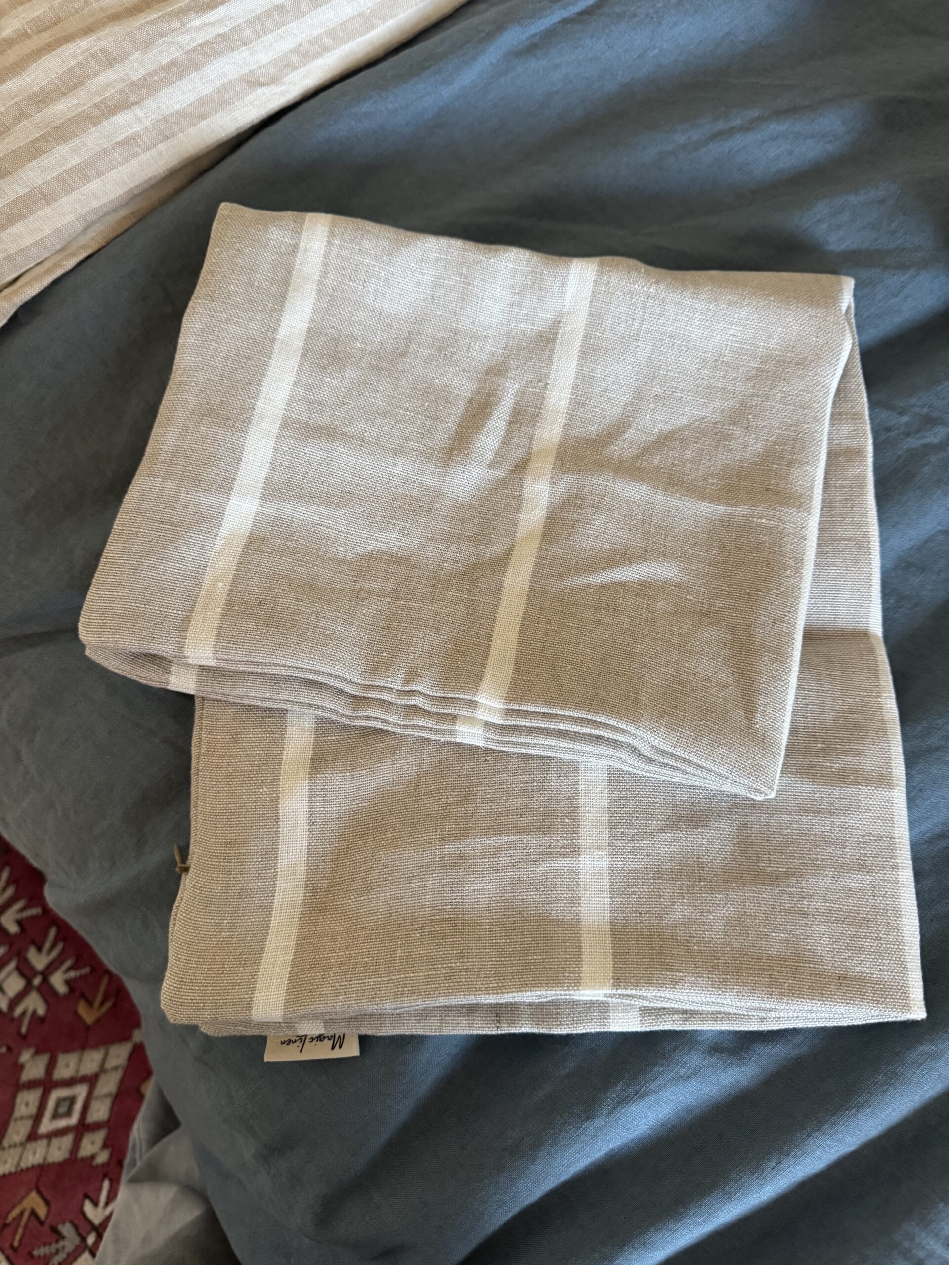A folded beige and white striped cloth napkin or towel is placed on a blue fabric surface.