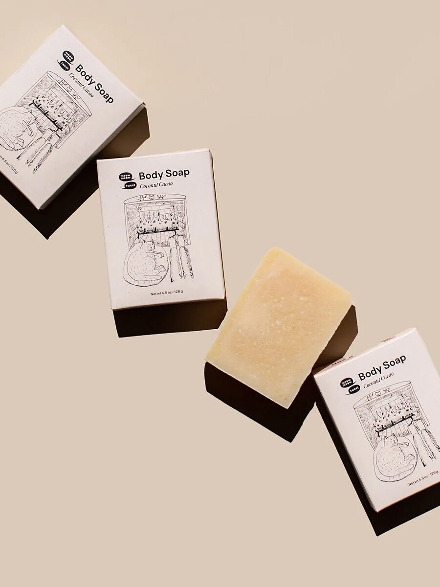 Meow Meow Tweet's soap bar packaging and soap laying down next to one another in a diagonal.