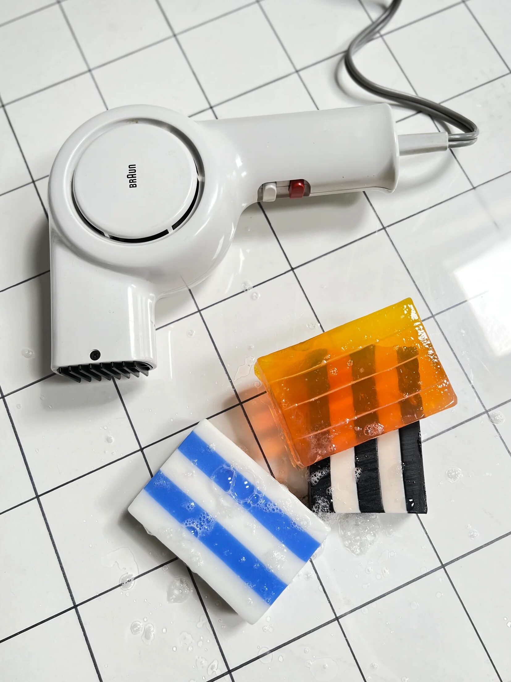 Three Wary Meyers soaps on the floor next to a white hair dryer.