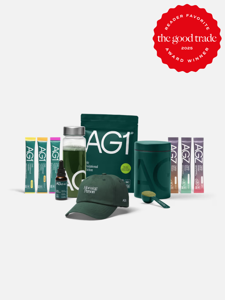 A collection of AG1 nutritional supplement products, including pouches, stick packs, a shaker bottle, a scoop, a cap, and a dropper, with an award badge in the top right corner.