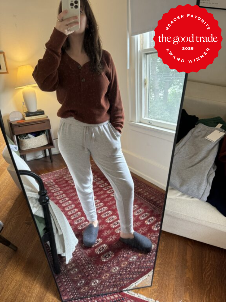 Person takes a mirror selfie in a bedroom, wearing a brown sweater, gray sweatpants, and slippers. A "The Good Trade 2025 Reader Favorite Award Winner" badge is in the corner.