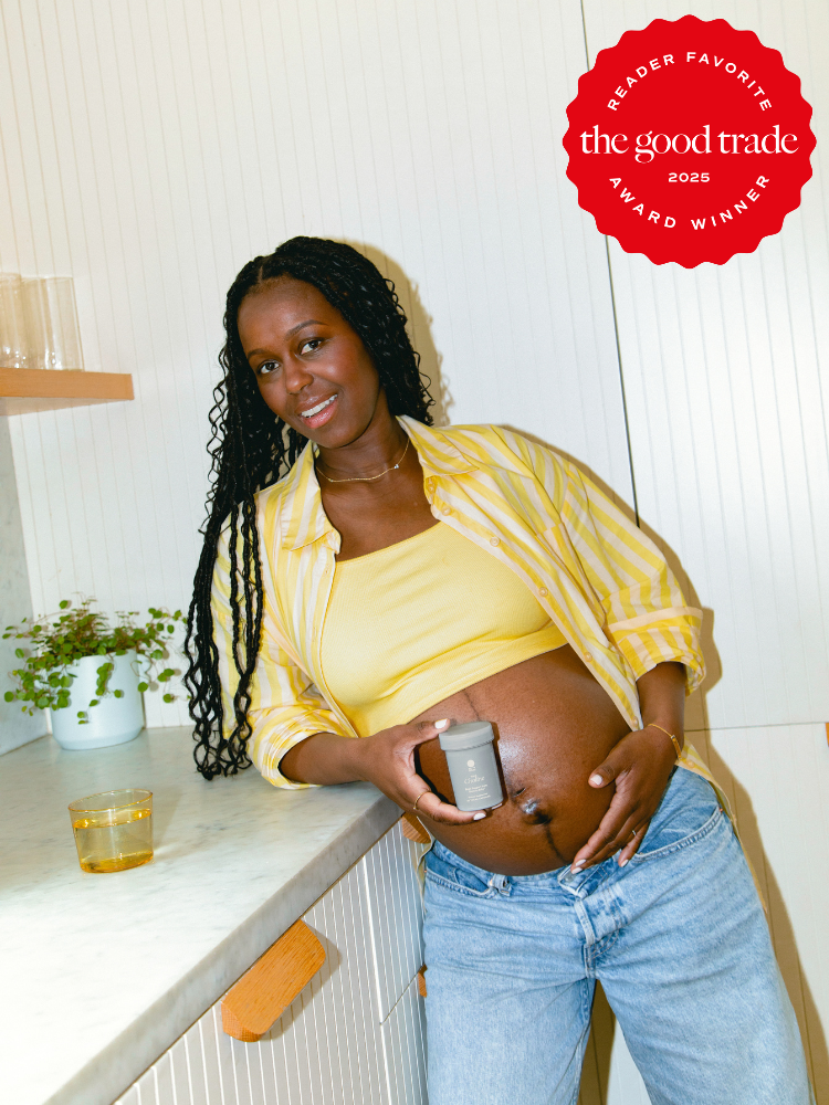 A pregnant woman in a yellow top and striped shirt stands in a kitchen, holding a skincare product to her belly. A "The Good Trade 2025 Award Winner" badge is in the upper right corner.